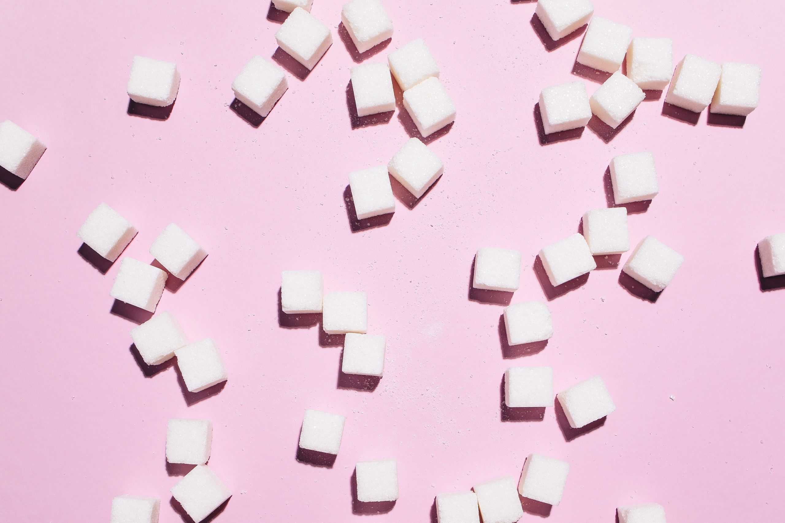 Kostičky cukru na růžovém pozadí